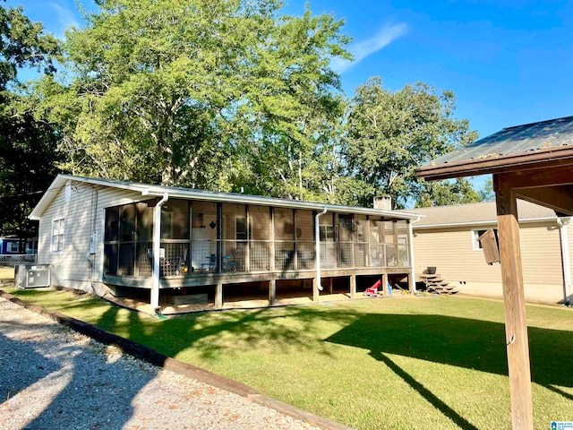 back of property featuring central AC unit, a sunroom, and a lawn