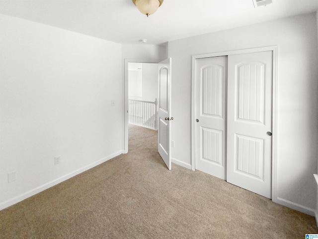 unfurnished bedroom featuring a closet and light colored carpet