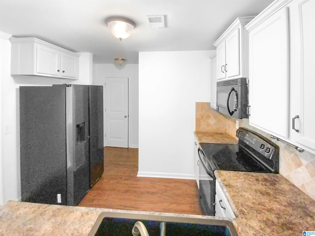 kitchen featuring light wood-type flooring, black appliances, backsplash, and white cabinets