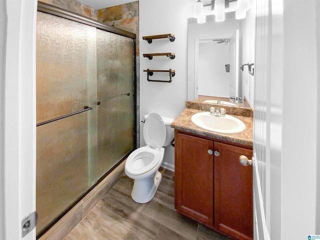 bathroom featuring vanity, toilet, hardwood / wood-style flooring, and an enclosed shower