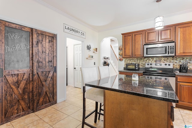 kitchen with a kitchen bar, a center island, stainless steel appliances, hanging light fixtures, and dark stone counters