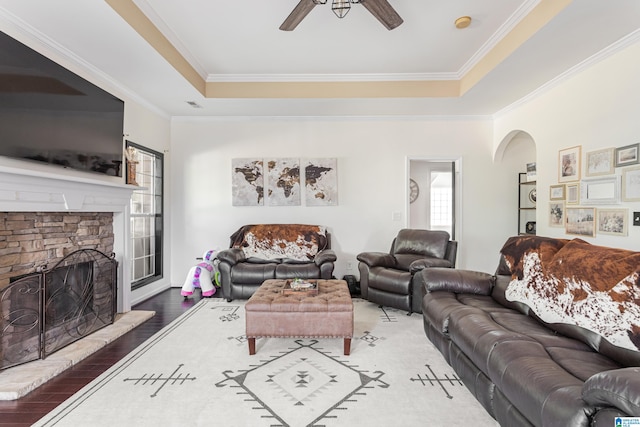 living room with a fireplace, a tray ceiling, ceiling fan, and light hardwood / wood-style floors