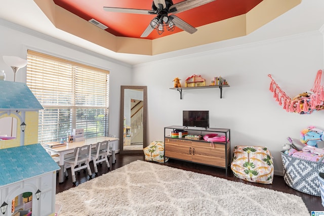 interior space featuring ornamental molding, a raised ceiling, dark hardwood / wood-style flooring, and ceiling fan