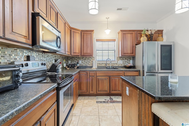 kitchen featuring backsplash, light tile patterned floors, appliances with stainless steel finishes, sink, and pendant lighting