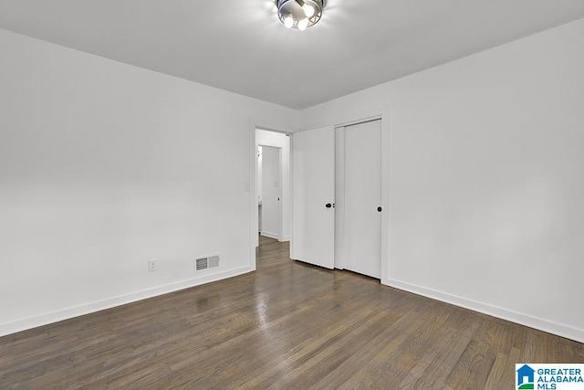 unfurnished bedroom featuring a closet and dark hardwood / wood-style floors