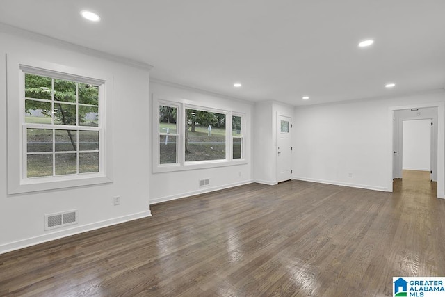 spare room featuring crown molding, a wealth of natural light, and dark hardwood / wood-style floors