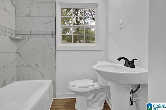 bathroom with toilet, hardwood / wood-style flooring, and tiled shower / bath