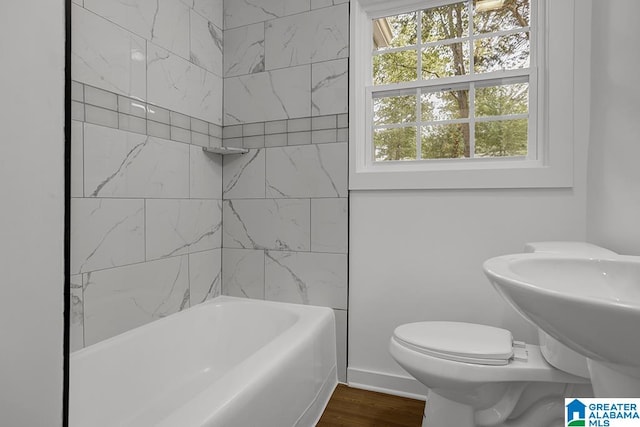 bathroom with hardwood / wood-style floors, toilet, and tiled shower / bath combo