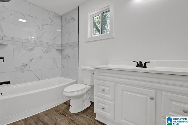 full bathroom featuring tiled shower / bath, toilet, hardwood / wood-style flooring, and vanity