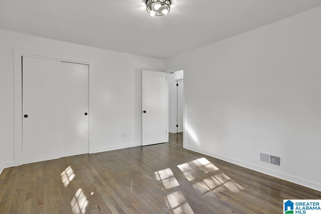 unfurnished bedroom featuring dark hardwood / wood-style flooring and a closet