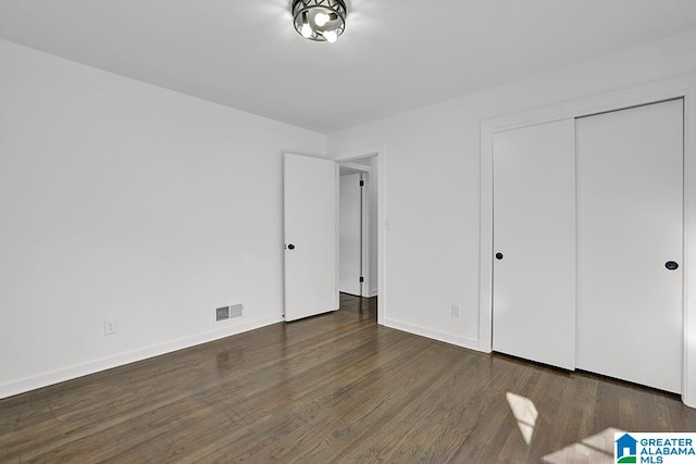 unfurnished bedroom with dark hardwood / wood-style flooring and a closet