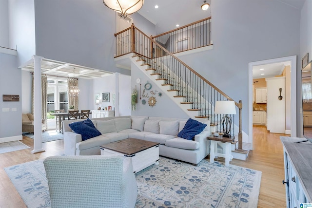 living room with light hardwood / wood-style flooring, a high ceiling, and a chandelier