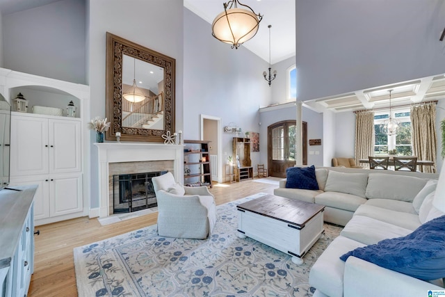 living room with a towering ceiling, light hardwood / wood-style flooring, and a chandelier