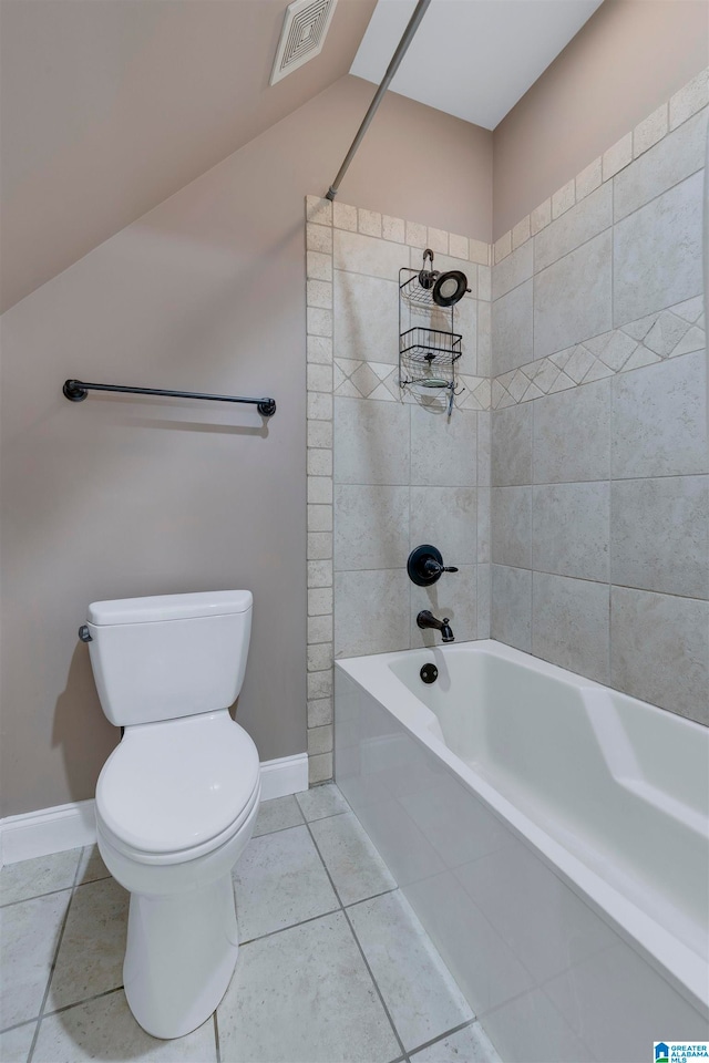 bathroom featuring tile patterned flooring, toilet, and tiled shower / bath combo