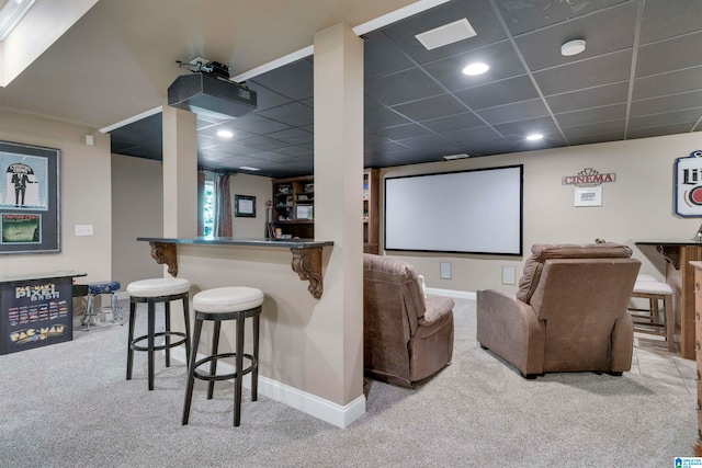 carpeted cinema room with bar area and a paneled ceiling