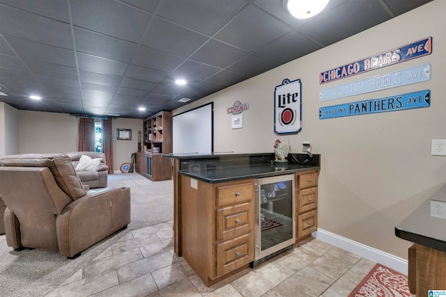 bar with beverage cooler, light colored carpet, and a drop ceiling