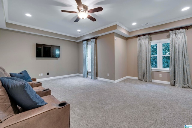 carpeted living room with ceiling fan, a raised ceiling, and crown molding