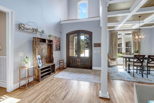 foyer featuring an inviting chandelier, light hardwood / wood-style flooring, beamed ceiling, ornate columns, and coffered ceiling