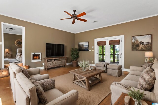 living room with crown molding, french doors, a fireplace, and ceiling fan