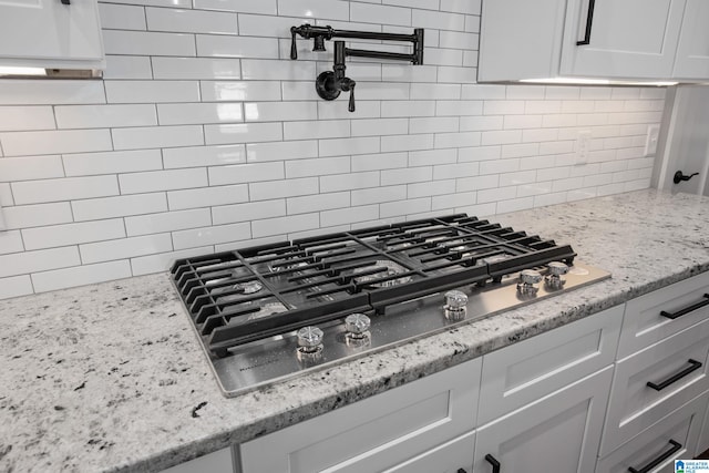 room details featuring stainless steel gas stovetop, light stone counters, and white cabinetry