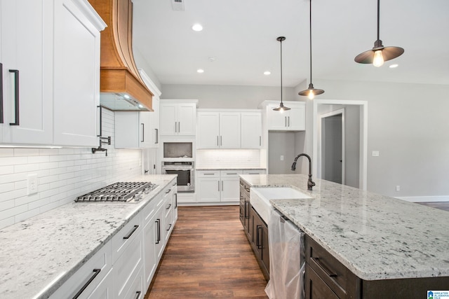 kitchen featuring a center island with sink, appliances with stainless steel finishes, hanging light fixtures, dark wood-type flooring, and white cabinetry