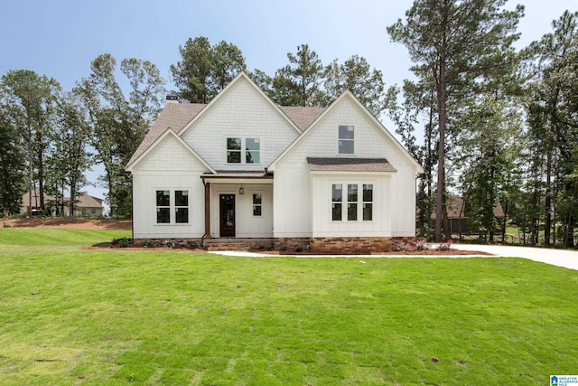 view of front facade featuring a chimney, a shingled roof, board and batten siding, and a front yard