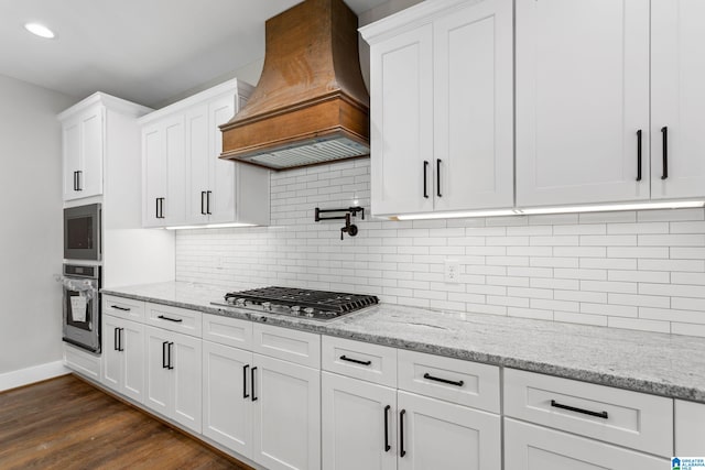 kitchen with stainless steel appliances, custom range hood, and white cabinetry