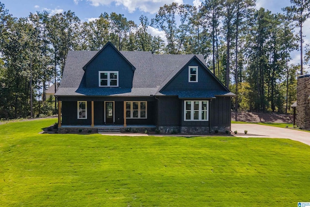 craftsman-style home featuring a shingled roof, covered porch, and a front lawn