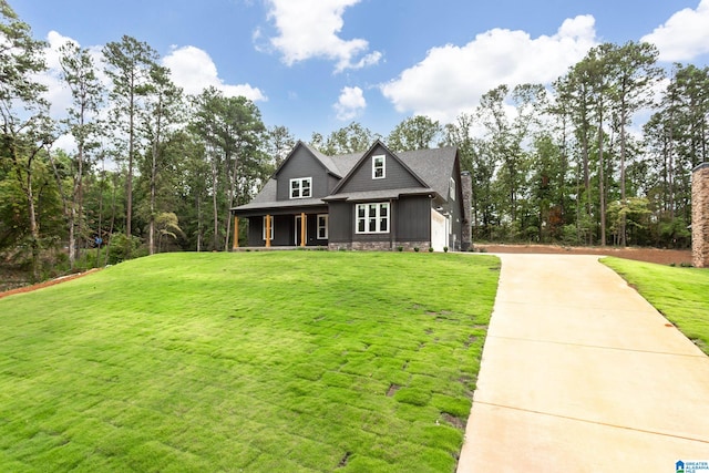 view of front of home featuring driveway, stone siding, and a front lawn