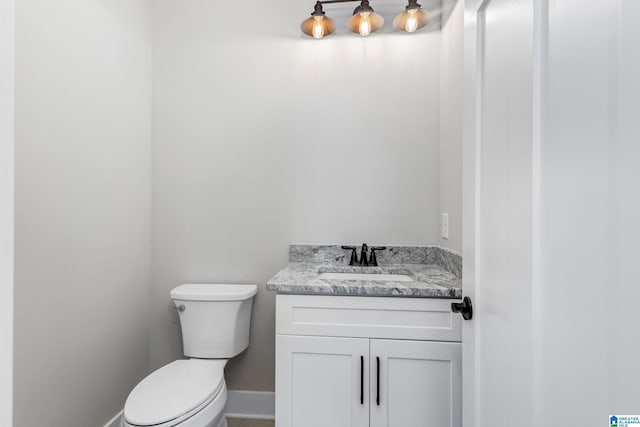 half bath featuring toilet, vanity, and baseboards