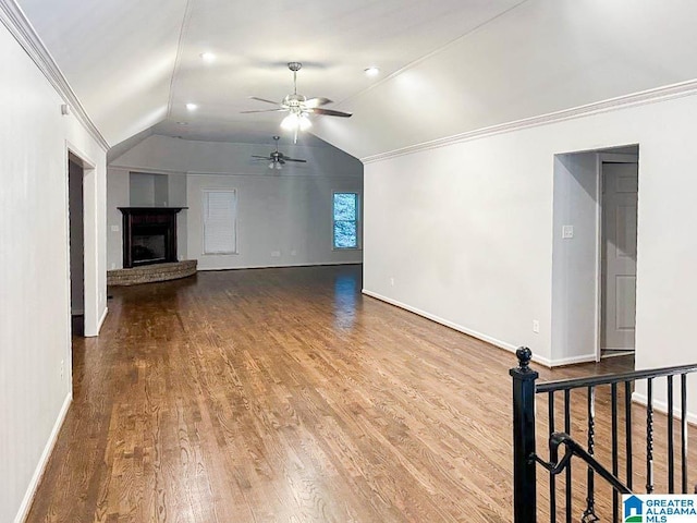 unfurnished living room with wood finished floors, a ceiling fan, baseboards, vaulted ceiling, and ornamental molding