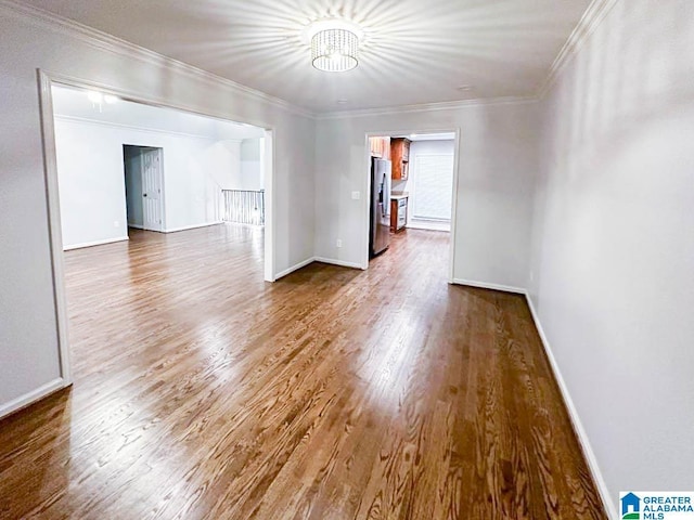 spare room featuring crown molding, baseboards, and wood finished floors