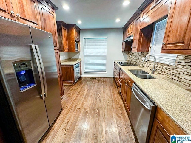 kitchen featuring stainless steel appliances, sink, light stone countertops, and light hardwood / wood-style floors