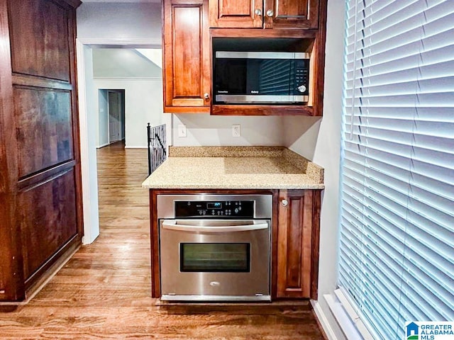 kitchen with hardwood / wood-style floors, stainless steel appliances, and light stone countertops