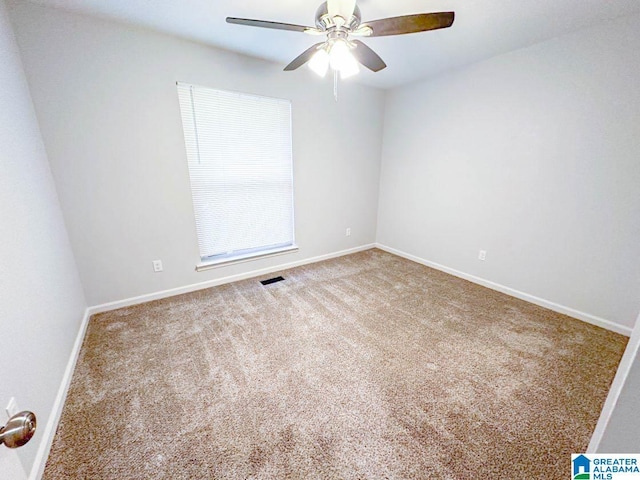 carpeted spare room with ceiling fan, visible vents, and baseboards