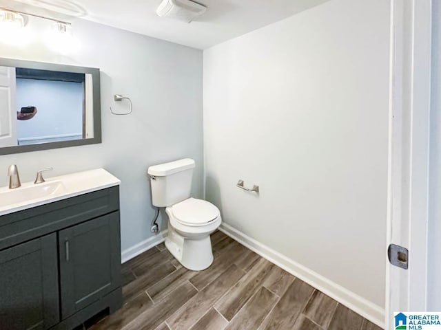 bathroom with visible vents, toilet, wood tiled floor, vanity, and baseboards