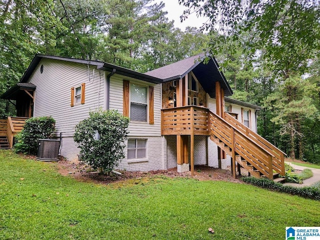 view of front of home featuring stairs, central AC unit, a front lawn, and brick siding