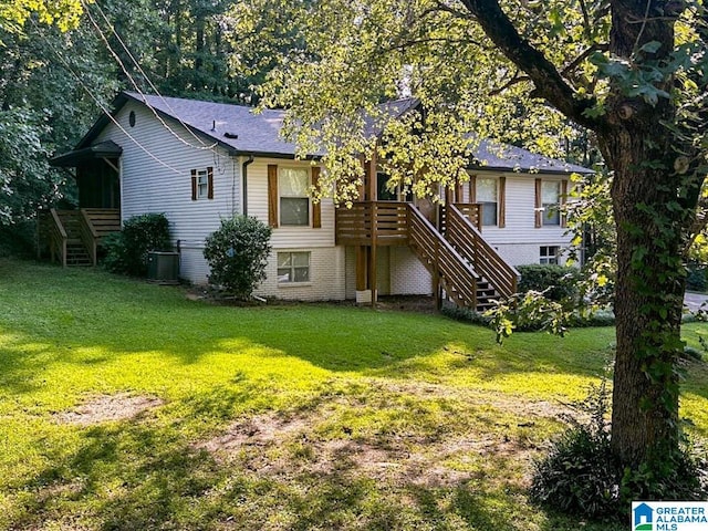 rear view of house with stairs, central AC, and a lawn