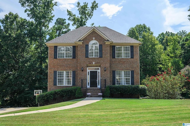 colonial home featuring a front lawn and brick siding