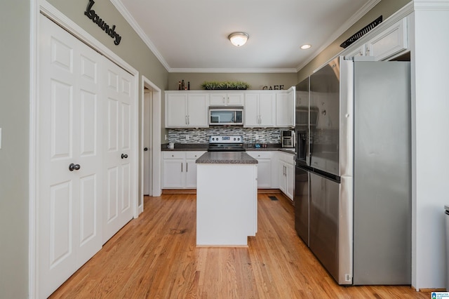 kitchen with white cabinets, dark countertops, appliances with stainless steel finishes, and a center island