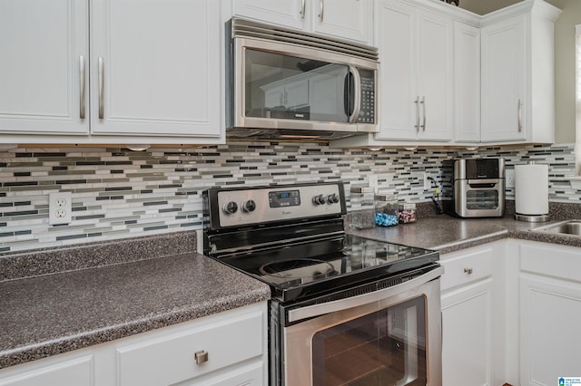 kitchen with backsplash, appliances with stainless steel finishes, and white cabinets