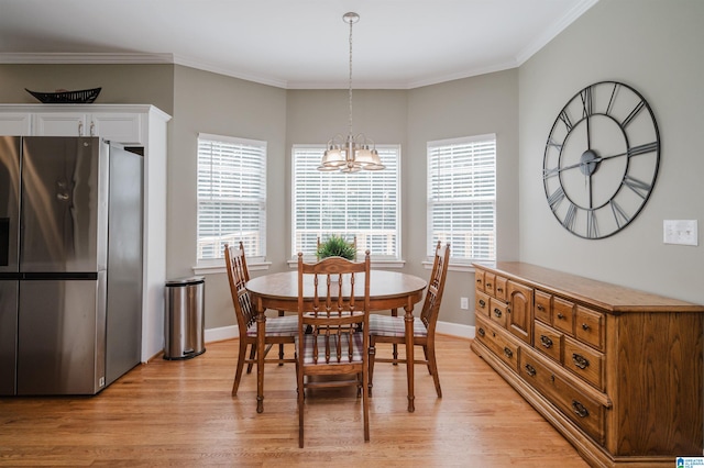 dining space featuring ornamental molding, light hardwood / wood-style floors, an inviting chandelier, and a healthy amount of sunlight