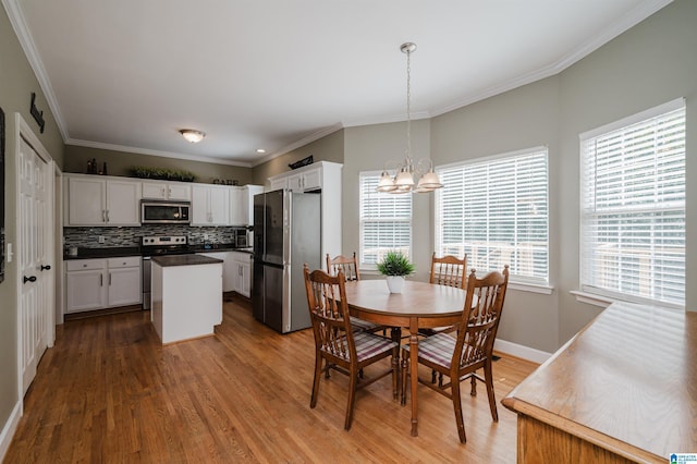 dining area with an inviting chandelier, crown molding, and wood finished floors