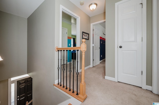 hall with carpet floors, baseboards, and an upstairs landing
