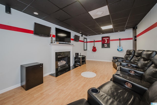 living area with baseboards, wood finished floors, and a paneled ceiling