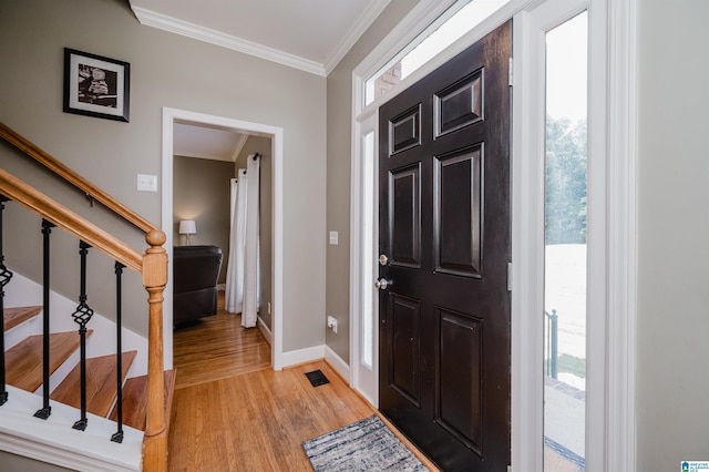 entrance foyer featuring baseboards, light wood-style floors, ornamental molding, and a healthy amount of sunlight