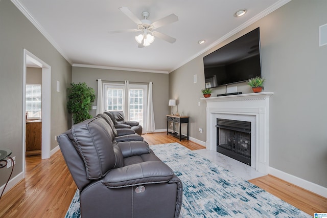 living room featuring light wood-type flooring, ceiling fan, and crown molding