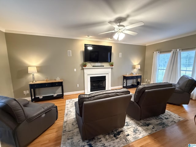 living area featuring a fireplace, light wood-type flooring, a ceiling fan, and ornamental molding
