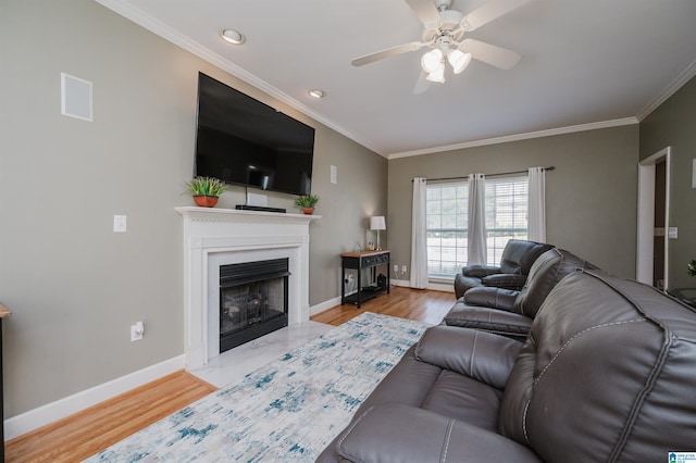 living room featuring light hardwood / wood-style flooring, ceiling fan, and crown molding