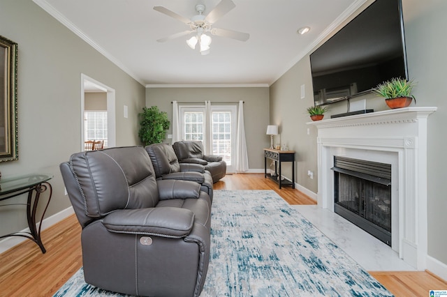 living room with ornamental molding, ceiling fan, and light hardwood / wood-style floors